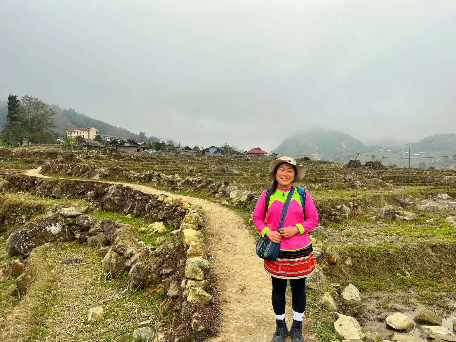 Nhu standing on a mountain path near a village in Sapa